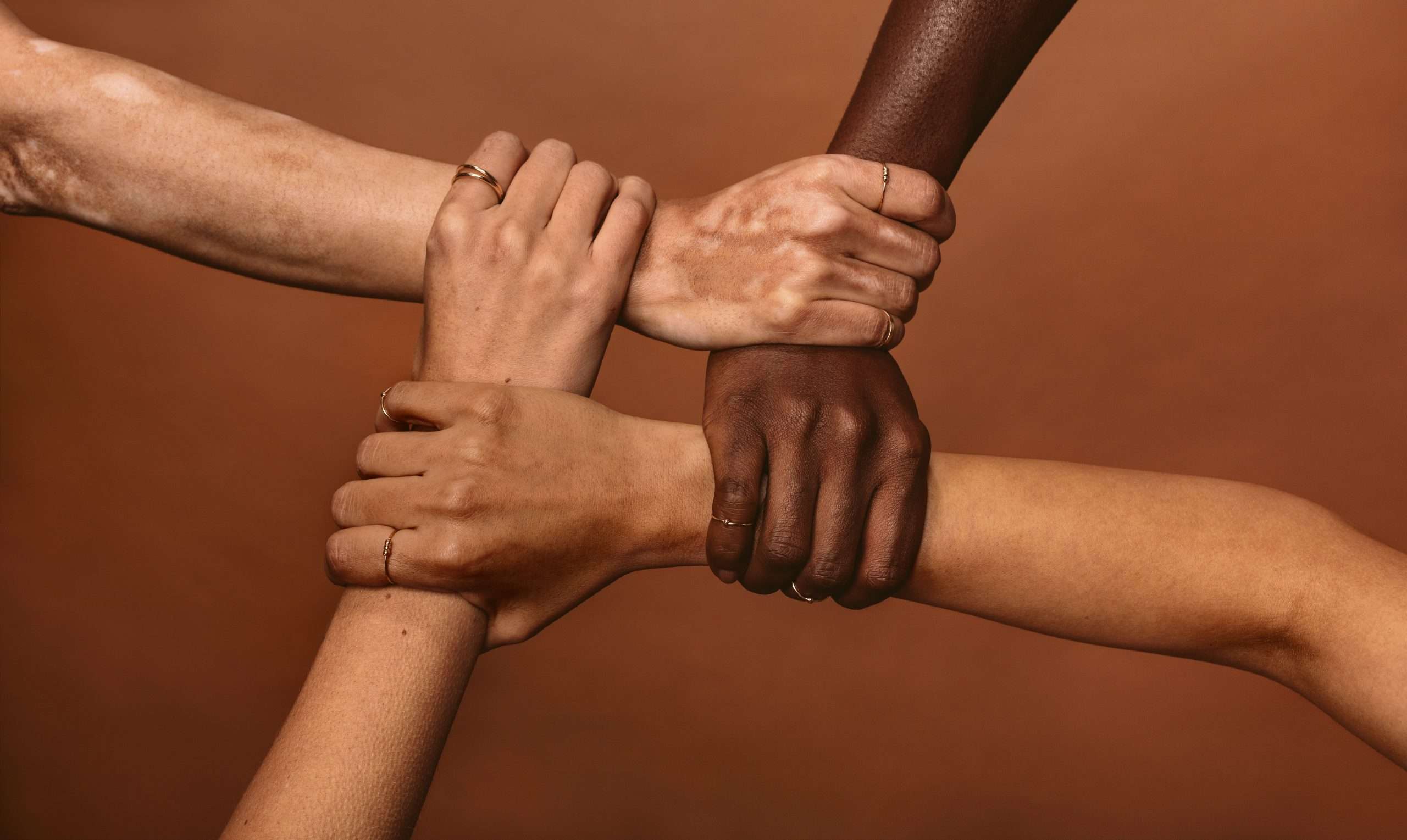 Four,Diverse,Women,Holding,Each,Others,Wrists,In,A,Circle.